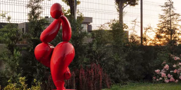 Kübra Doğu imzalı parlak kırmızı heykel, villanın doğal peyzajı içinde güçlü bir odak noktası oluşturarak mekâna çağdaş ve dinamik bir karakter katıyor. Organik formu ve rengi, yeşil dokuya kontrastla uyum sağlayarak dış mekânda dengeli ve etkileyici bir bütünlük yaratıyor. Eser Muse Contemporary’dan alınmış.