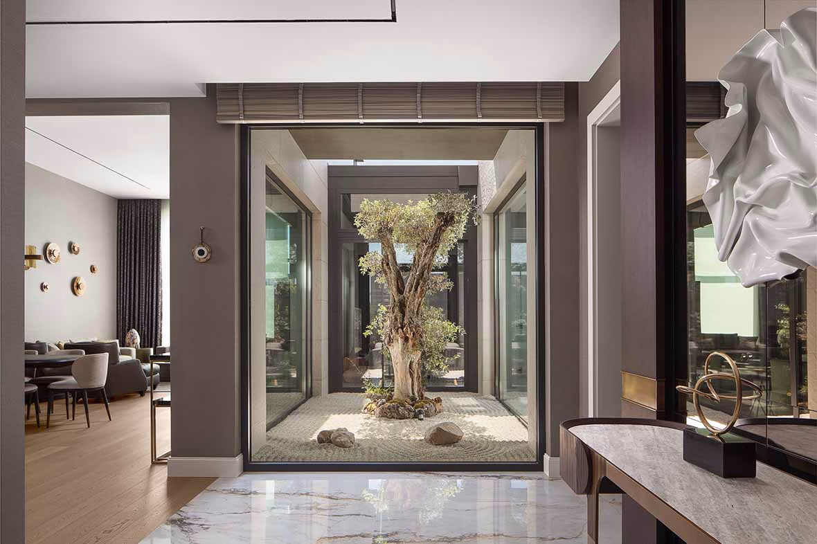 Evin en önemli odak noktası, giriş holünde yer alan zeytin ağacı. Zeytinin bilgeliği, sakinliği ve asaleti, projenin tüm tasarım dilini ve hikayesini şekillendirmiş.